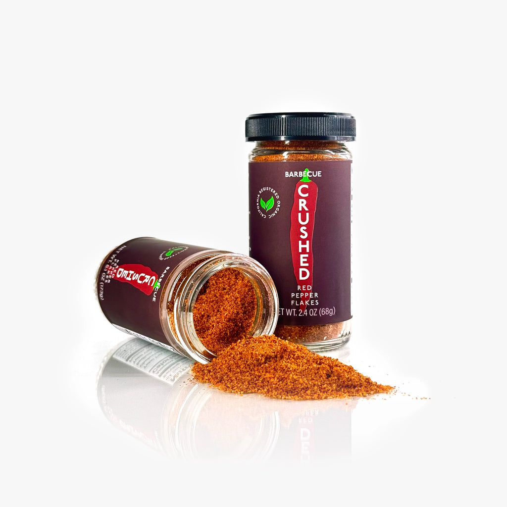 2 jars of Barbecue Crushed Red Pepper Flakes on a white background, one on its side with the contents spilling out.