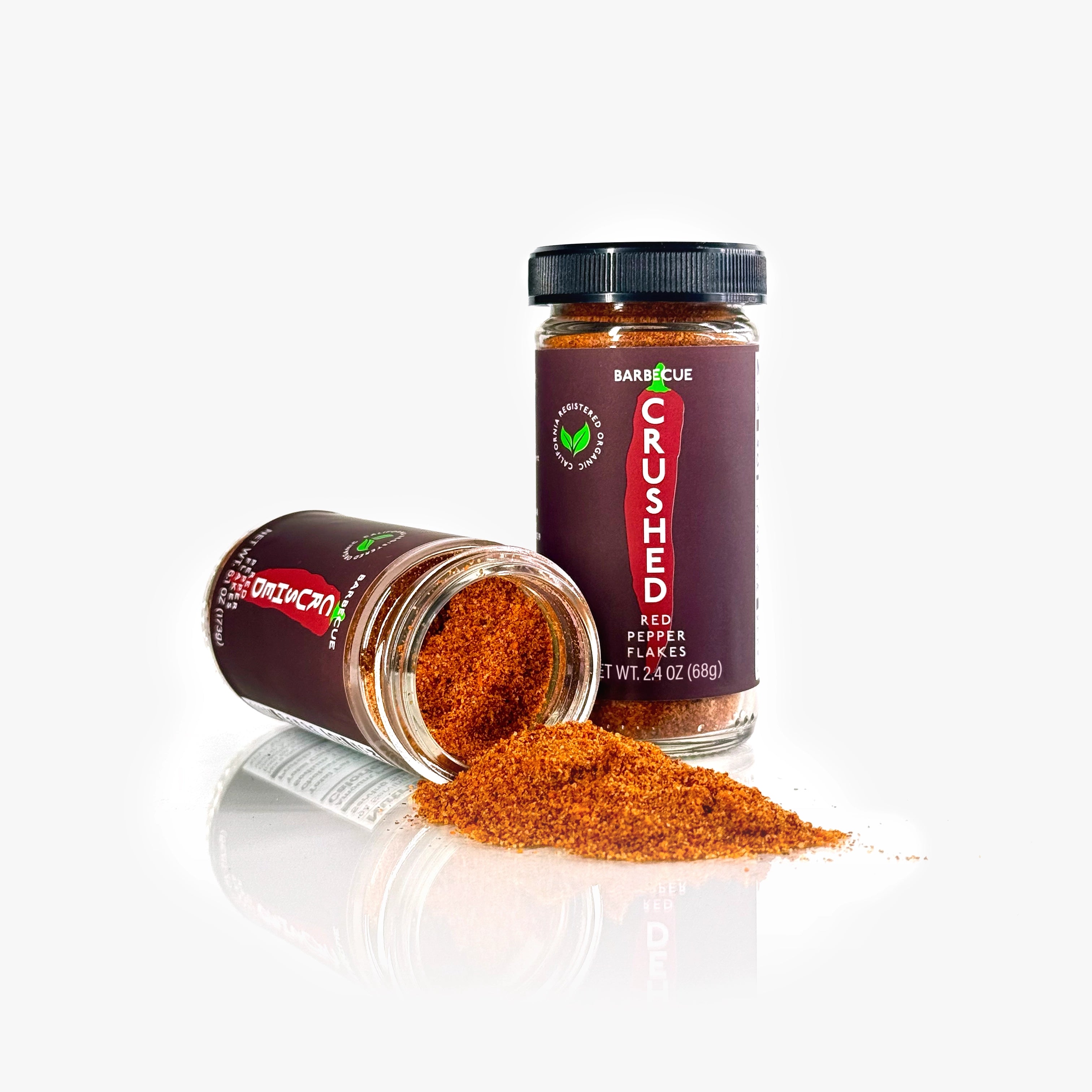 2 jars of Barbecue Crushed Red Pepper Flakes on a white background, one on its side with the contents spilling out.