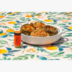 Jar of Crushed Cheddar Red Pepper shown next to roasted artichokes on a colorful Italian table cloth