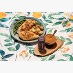 Plated dish of chicken with green beans and mushrooms on a floral tablecloth, accompanied by a jar of Barbecue Crushed Red Pepper.