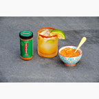 Jar of Chili Lime Crushed Red Pepper,  margarita cocktail with lime and chili lime spice rim, and bowl of Chili Lime Crushed Red Pepper on a gray slate surface.